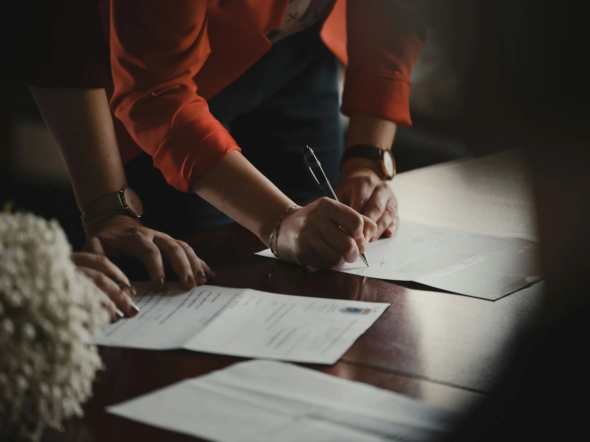 Two people leaning over a table to sign papers