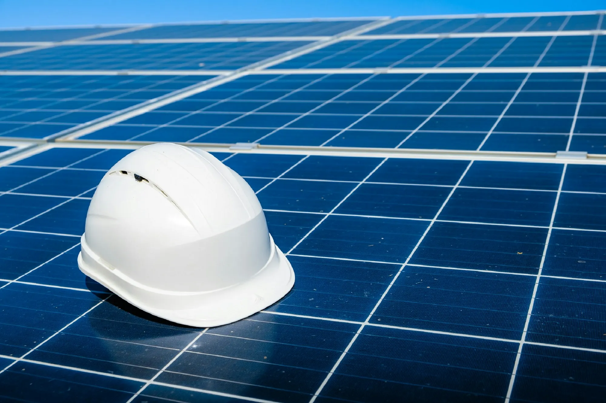 White hard hat resting on a blue solar panel